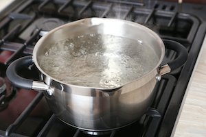 Water boiling into saucepan on the gas stove