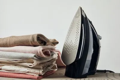 Iron and folded ironed clothes on ironing board