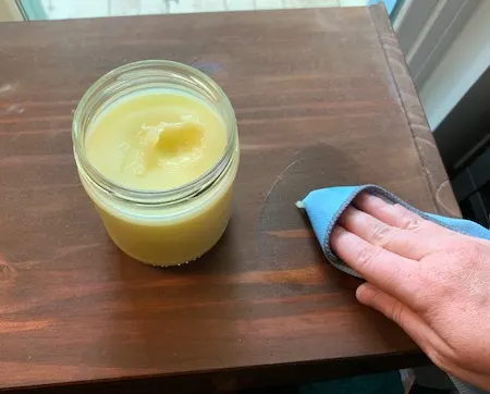 Person wiping homemade furniture polish on wooden table